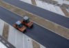 aerial view of orange vibratory asphalt roller compactor on a new pavement