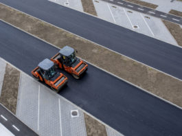 aerial view of orange vibratory asphalt roller compactor on a new pavement